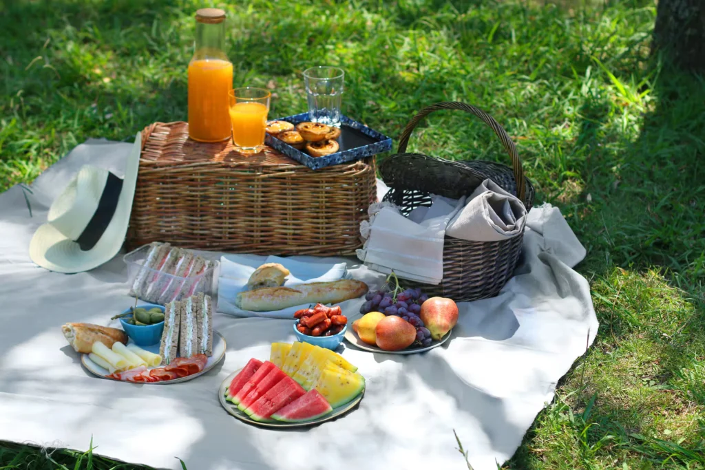Picnic setup with food and basket in green outdoor park setting